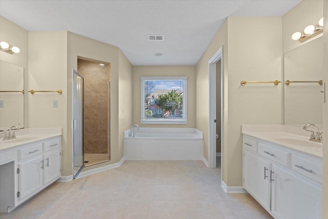 bathroom with a textured ceiling, independent shower and bath, and vanity