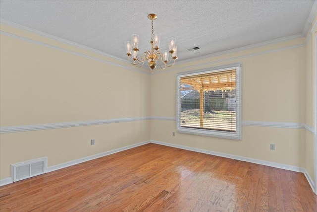 empty room with a notable chandelier, crown molding, a textured ceiling, and hardwood / wood-style flooring