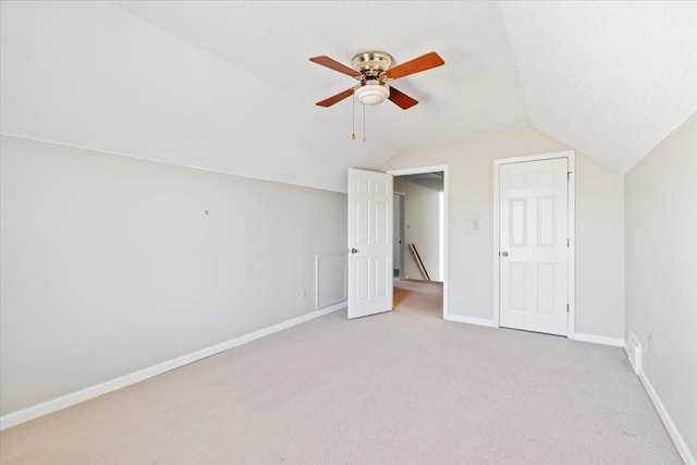 additional living space with a textured ceiling, lofted ceiling, and light colored carpet