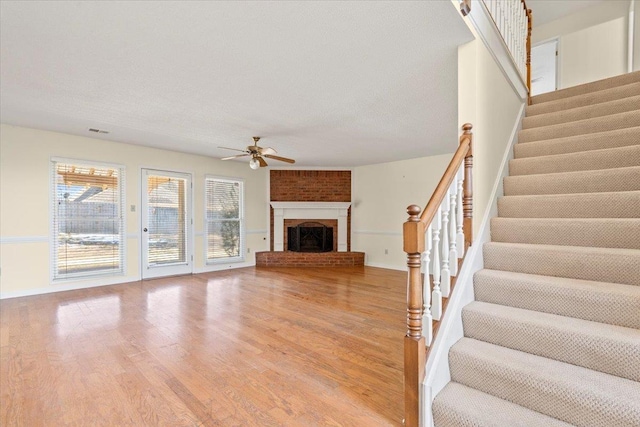 unfurnished living room featuring ceiling fan, a fireplace, and hardwood / wood-style flooring