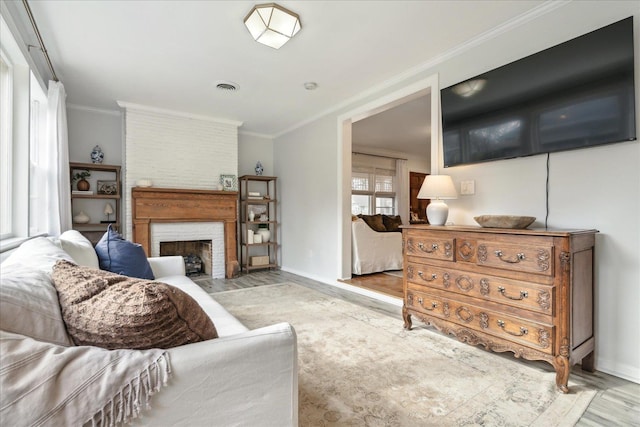 living room with light hardwood / wood-style floors, a large fireplace, and ornamental molding