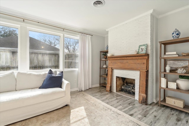 living room featuring light hardwood / wood-style flooring, crown molding, and a fireplace