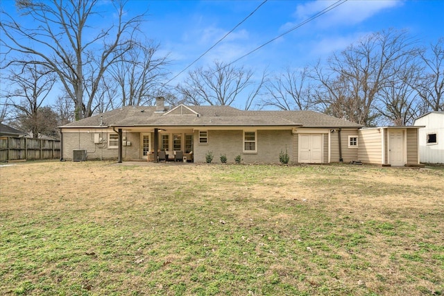 back of property featuring central air condition unit, a patio area, a lawn, and a storage unit