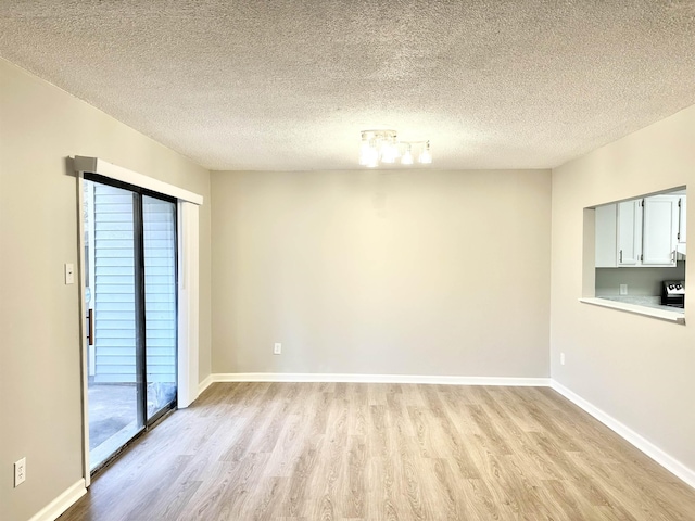 spare room featuring a textured ceiling and light hardwood / wood-style floors