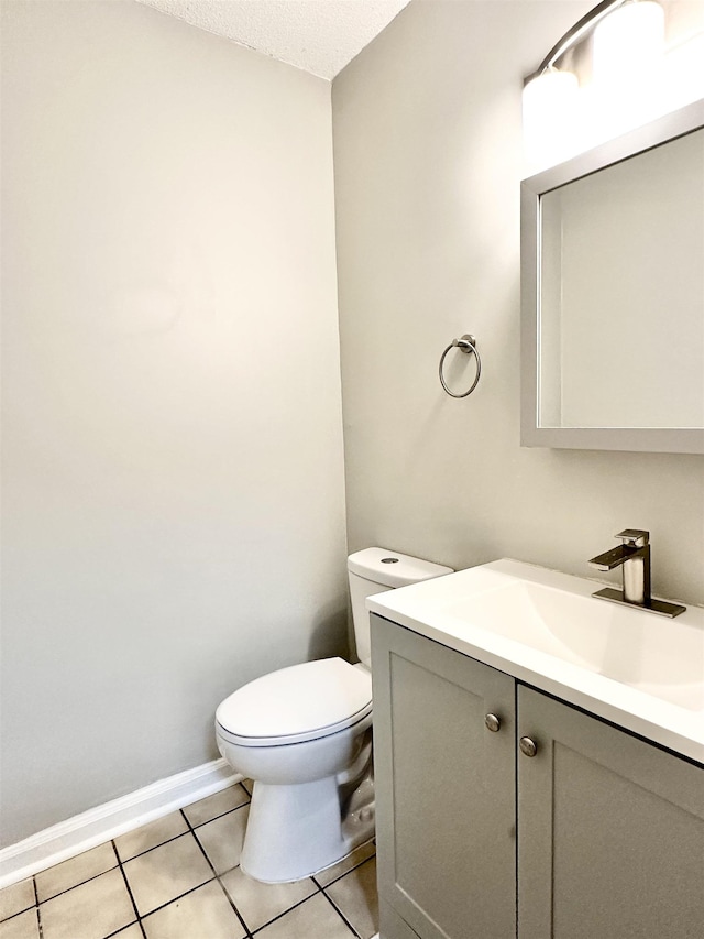 bathroom with a textured ceiling, toilet, tile patterned flooring, and vanity