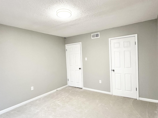 unfurnished bedroom featuring light colored carpet and a textured ceiling