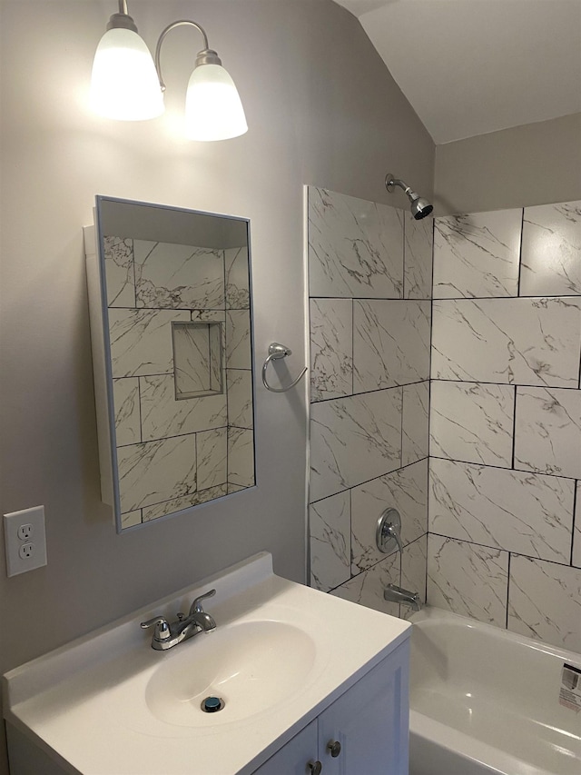 bathroom with tiled shower / bath, vaulted ceiling, and vanity