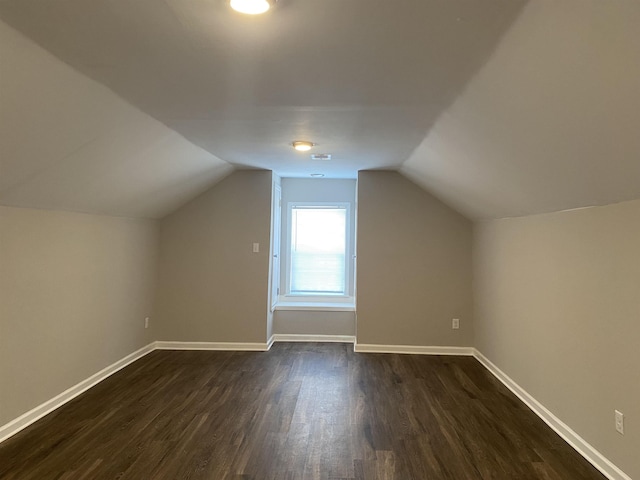 additional living space with dark wood-type flooring and vaulted ceiling