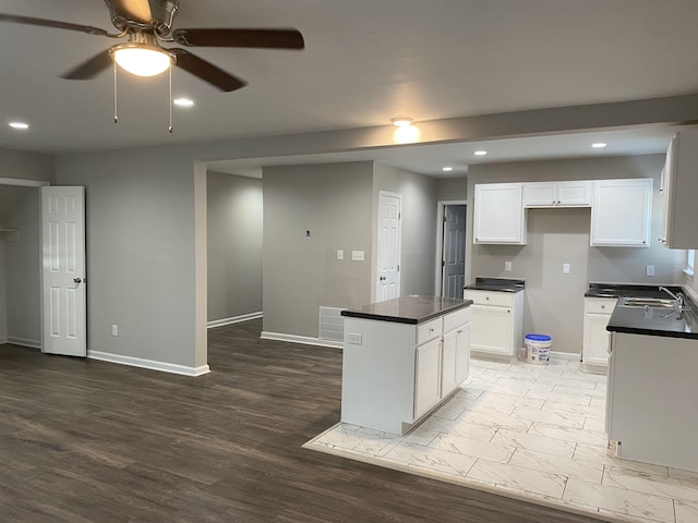 kitchen featuring ceiling fan, sink, white cabinets, and a center island