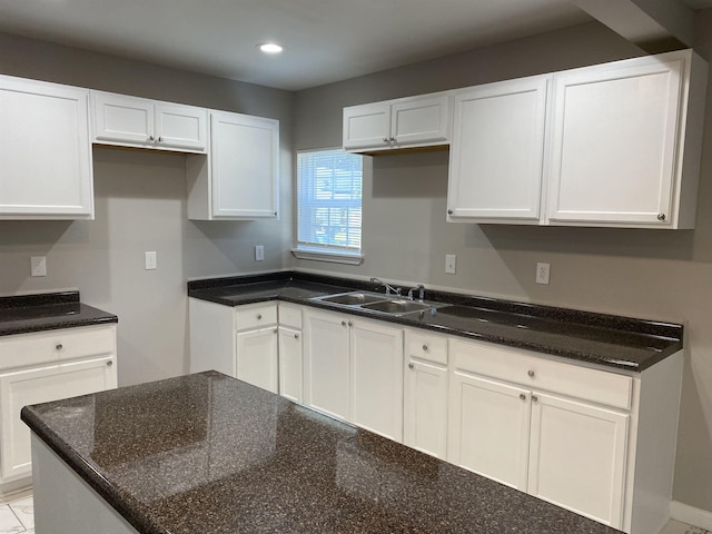 kitchen featuring sink, white cabinetry, and dark stone countertops