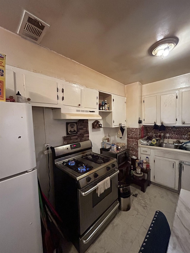 kitchen featuring sink, white cabinets, white fridge, and stainless steel gas range oven