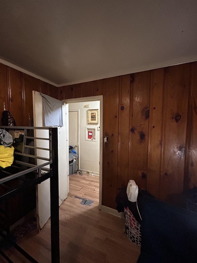 bedroom featuring wooden walls, ornamental molding, and hardwood / wood-style floors