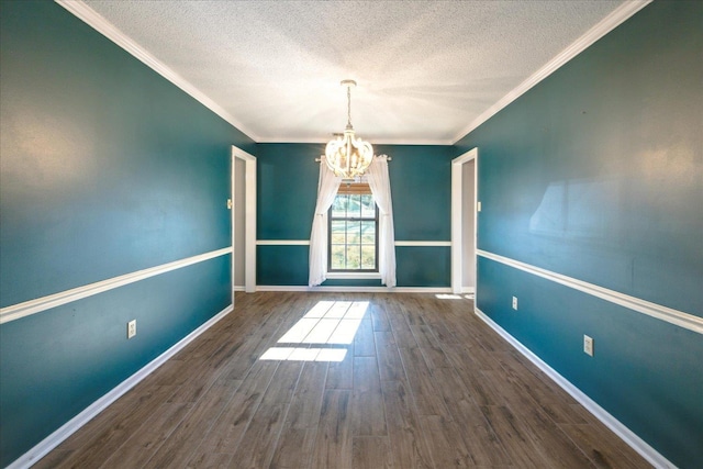 spare room featuring a textured ceiling, dark hardwood / wood-style flooring, ornamental molding, and a notable chandelier