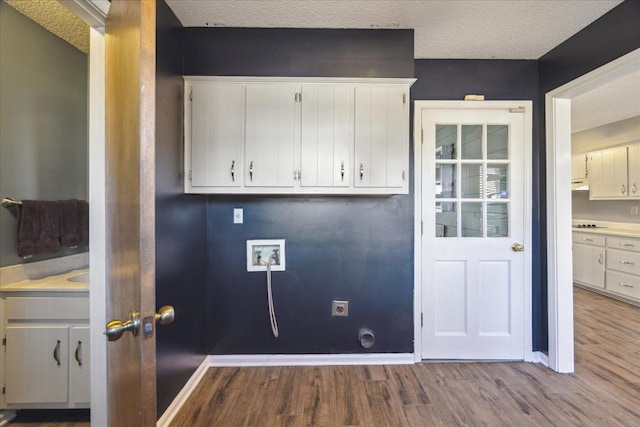 laundry room with a textured ceiling, cabinets, hookup for a washing machine, hookup for an electric dryer, and light hardwood / wood-style flooring