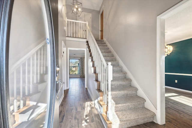 stairway featuring hardwood / wood-style floors and a notable chandelier