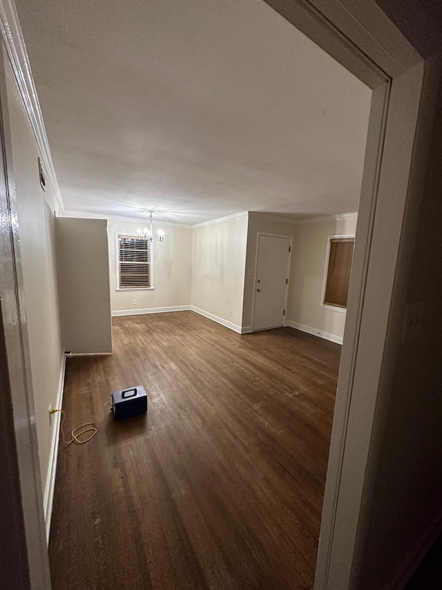 unfurnished living room featuring dark wood-type flooring, a notable chandelier, and ornamental molding