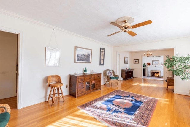 living room featuring hardwood / wood-style flooring, crown molding, and ceiling fan with notable chandelier