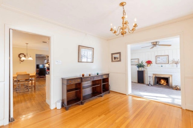 interior space with ceiling fan with notable chandelier, wood-type flooring, and crown molding