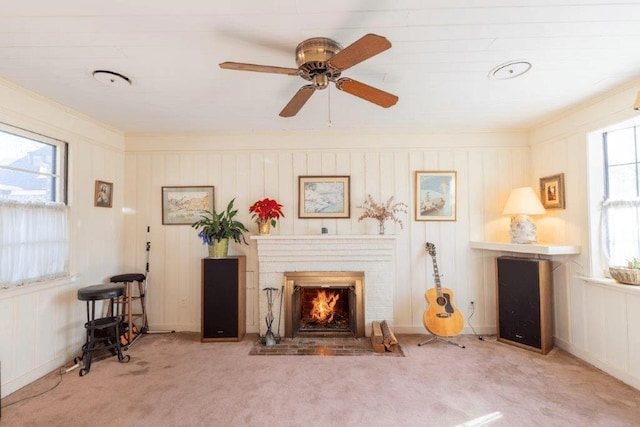 living area with light carpet, ceiling fan, a brick fireplace, and a wealth of natural light