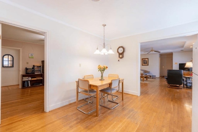 dining room with light hardwood / wood-style floors, a tray ceiling, ornamental molding, and ceiling fan with notable chandelier