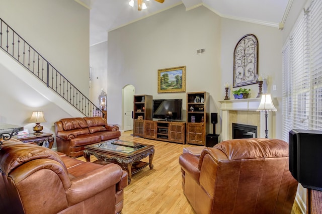 living room featuring light wood-type flooring, high vaulted ceiling, crown molding, and a fireplace