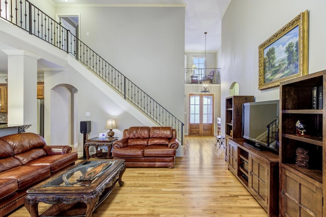 living room featuring light hardwood / wood-style floors, a high ceiling, and ornamental molding