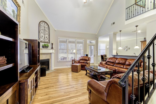 living room with crown molding, sink, a fireplace, high vaulted ceiling, and light hardwood / wood-style floors