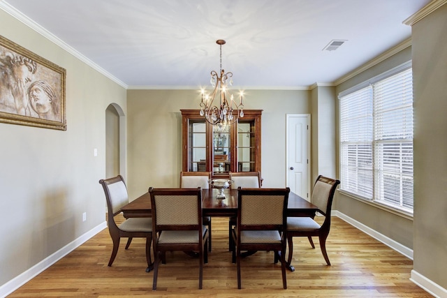 dining room featuring crown molding, plenty of natural light, an inviting chandelier, and light hardwood / wood-style floors