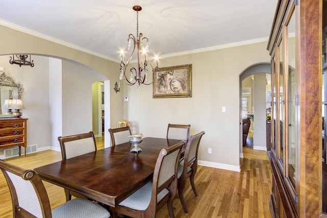 dining room with light hardwood / wood-style flooring, ornamental molding, and a chandelier