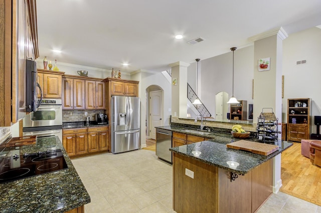 kitchen featuring kitchen peninsula, pendant lighting, sink, dark stone countertops, and stainless steel appliances