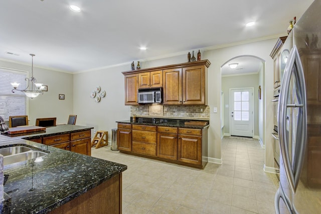 kitchen featuring crown molding, sink, decorative light fixtures, dark stone counters, and stainless steel appliances