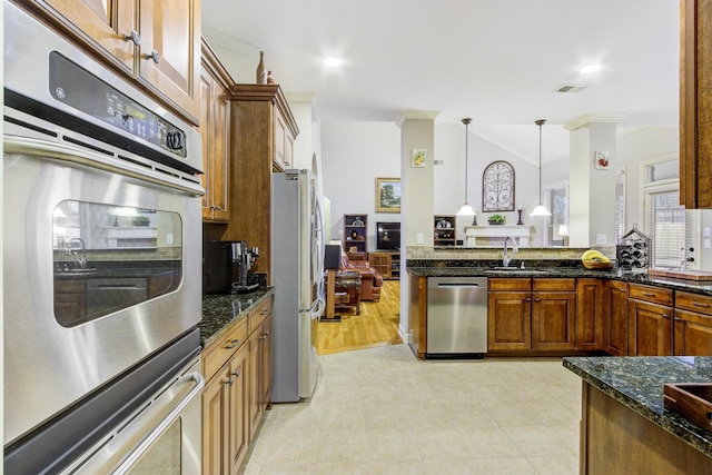 kitchen with appliances with stainless steel finishes, dark stone countertops, sink, hanging light fixtures, and ornamental molding