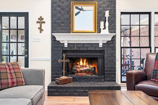 sitting room with hardwood / wood-style floors and a brick fireplace