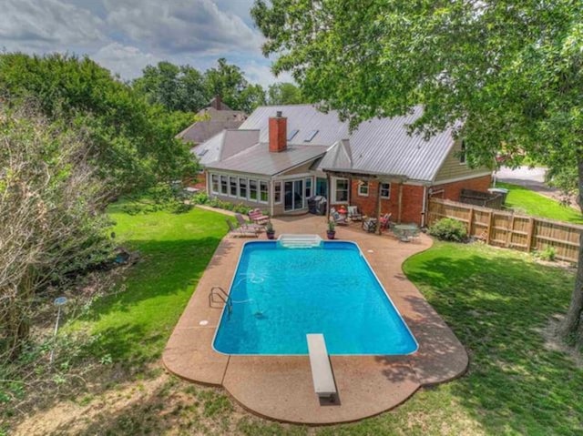 view of pool with a diving board, a patio area, and a lawn