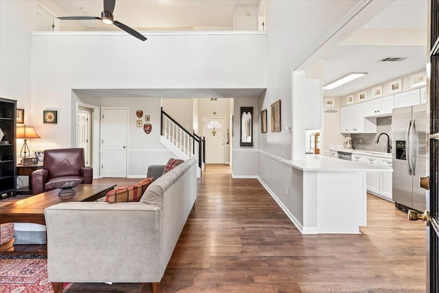 living room featuring sink, hardwood / wood-style flooring, a towering ceiling, and ceiling fan