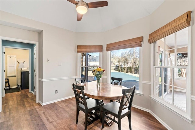 dining space with ceiling fan, vaulted ceiling, washer / clothes dryer, and dark wood-type flooring