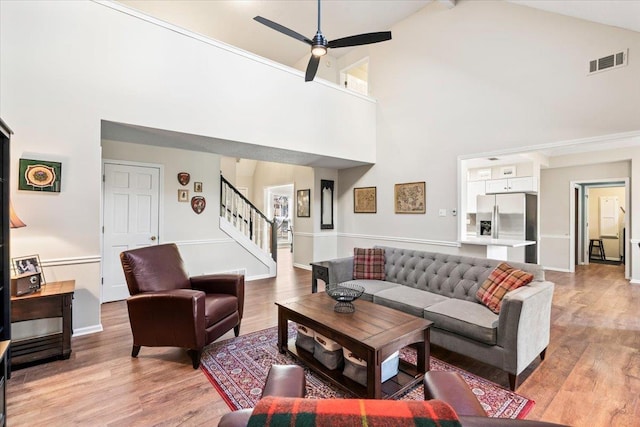 living room featuring light wood-type flooring, beamed ceiling, high vaulted ceiling, and ceiling fan