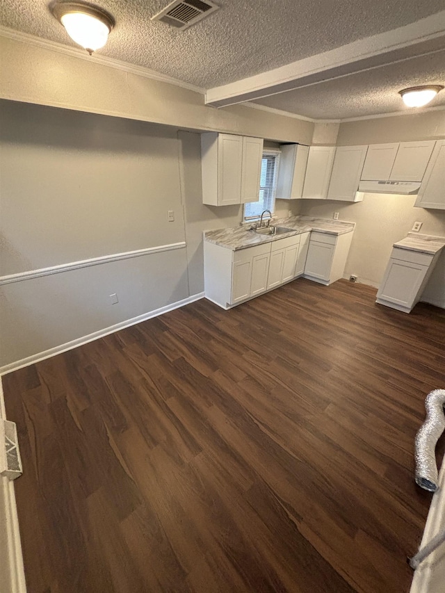 kitchen with crown molding, dark hardwood / wood-style flooring, sink, white cabinetry, and a textured ceiling