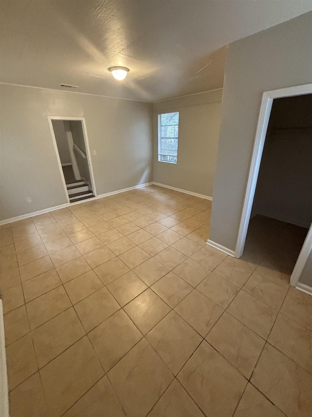 tiled spare room with a textured ceiling and built in shelves