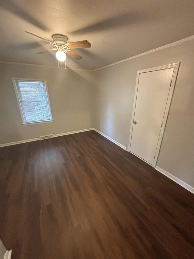 unfurnished room featuring ceiling fan, dark wood-type flooring, and crown molding