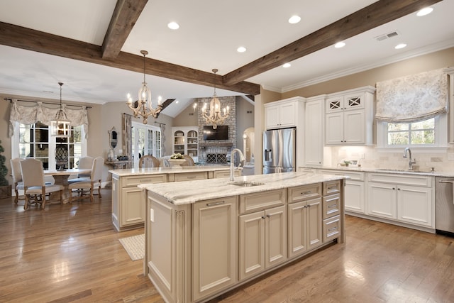 kitchen with a notable chandelier, a kitchen island with sink, sink, decorative light fixtures, and stainless steel appliances