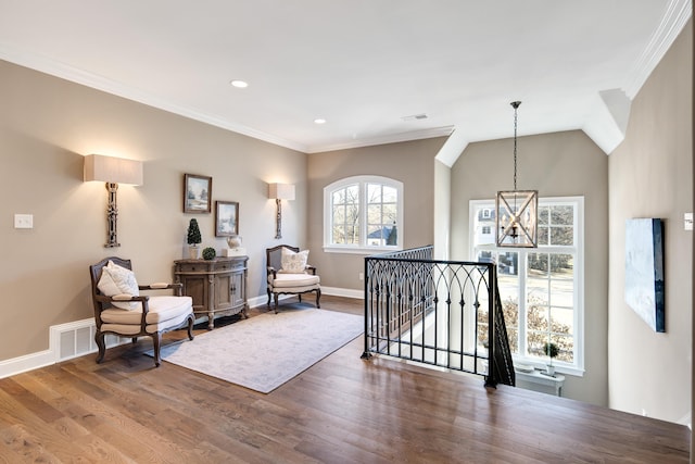 sitting room with hardwood / wood-style floors, crown molding, an inviting chandelier, and lofted ceiling