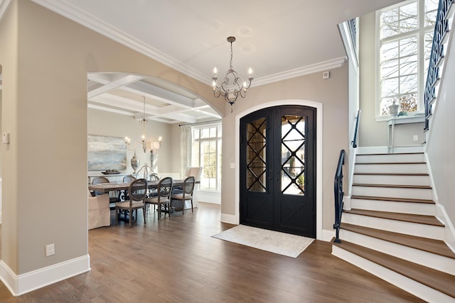 foyer entrance featuring coffered ceiling, beam ceiling, an inviting chandelier, ornamental molding, and dark hardwood / wood-style flooring