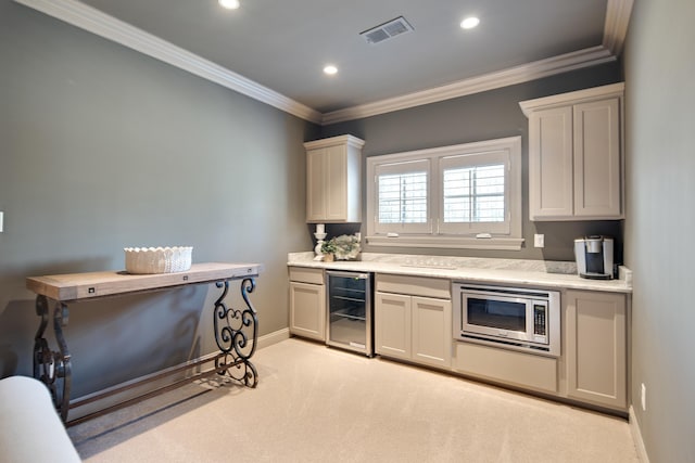 kitchen featuring light colored carpet, crown molding, beverage cooler, and stainless steel microwave