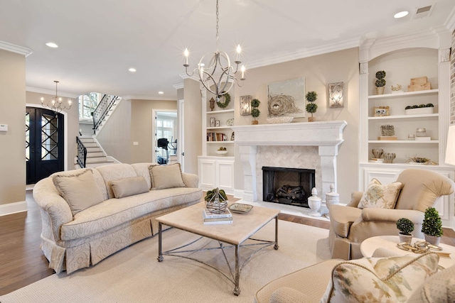 living room featuring ornamental molding, a chandelier, hardwood / wood-style floors, and a premium fireplace