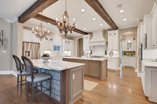 kitchen with white cabinets, stainless steel appliances, decorative backsplash, a large island, and custom range hood