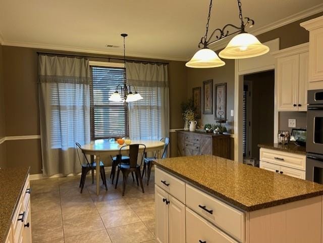 kitchen with pendant lighting, white cabinets, a kitchen island, light tile patterned floors, and crown molding