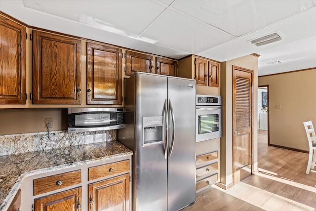 kitchen featuring light stone counters, light hardwood / wood-style flooring, and appliances with stainless steel finishes