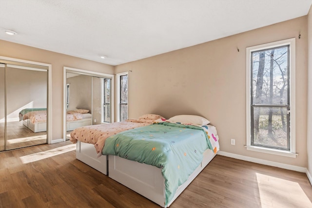 bedroom featuring hardwood / wood-style flooring and two closets