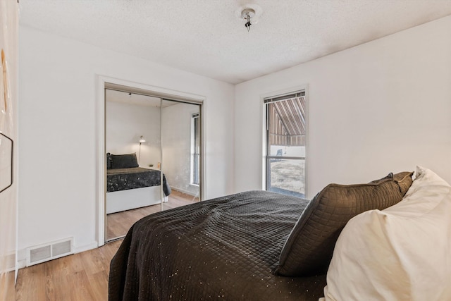 bedroom featuring a closet, light hardwood / wood-style floors, and a textured ceiling